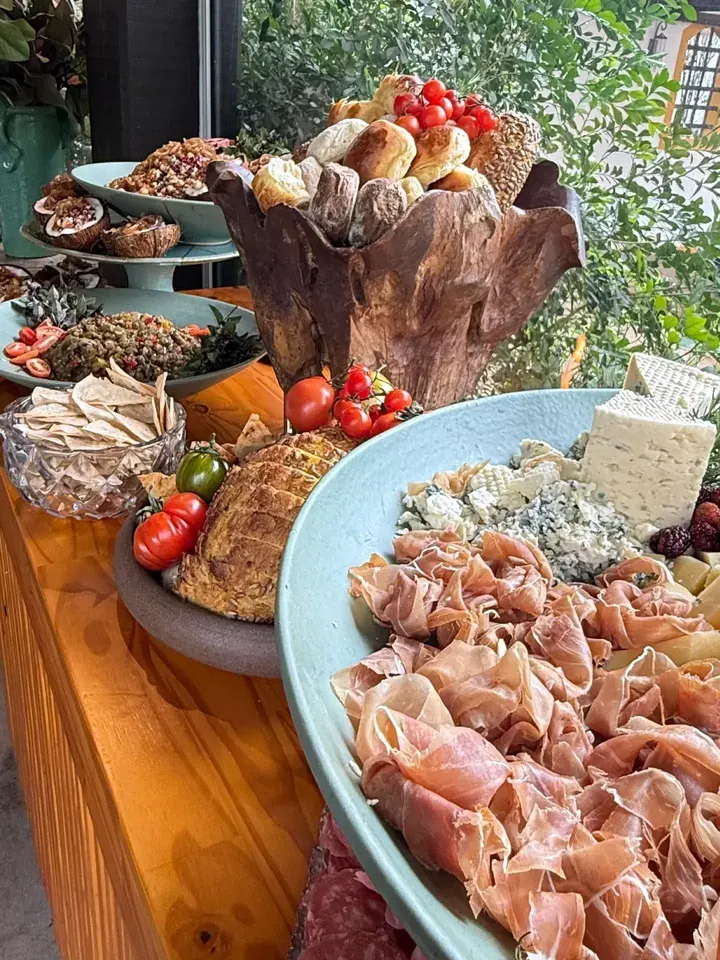 Mesa com presunto, queijos e uma seleção de pães