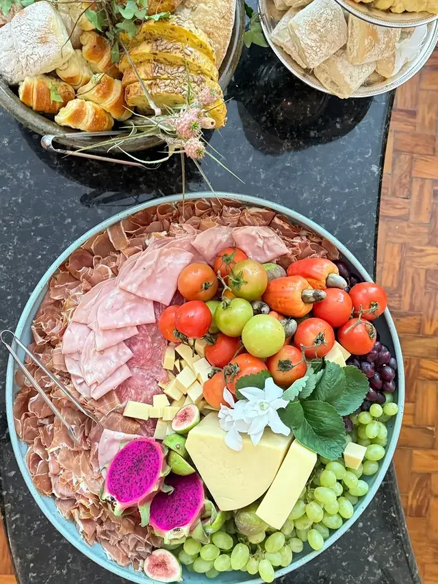 Vista de cima de uma composição de queijos, frios e frutas