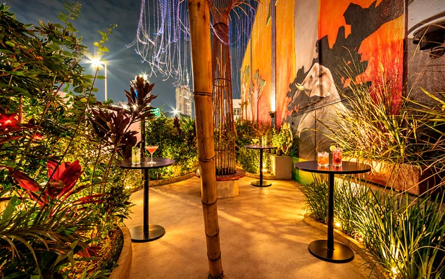Praça do jardim com painel de elefante, vegetação e mesas de apoio