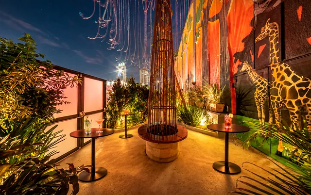 Praça do jardim com painel de girafas e iluminação acolhedora